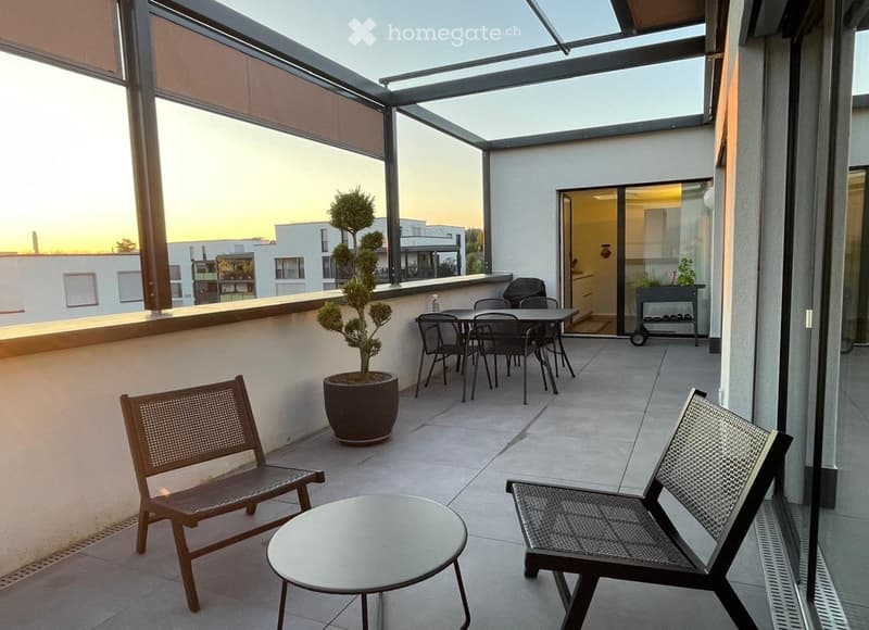 A modern rooftop terrace with a glass ceiling, featuring a round table, two chairs, a potted tree, and a dining set with four chairs and a table.