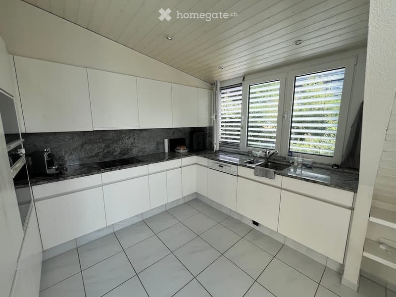 Modern kitchen with white cabinets, granite countertops, and stainless steel appliances. Features a sink, faucet, oven, and coffee maker.