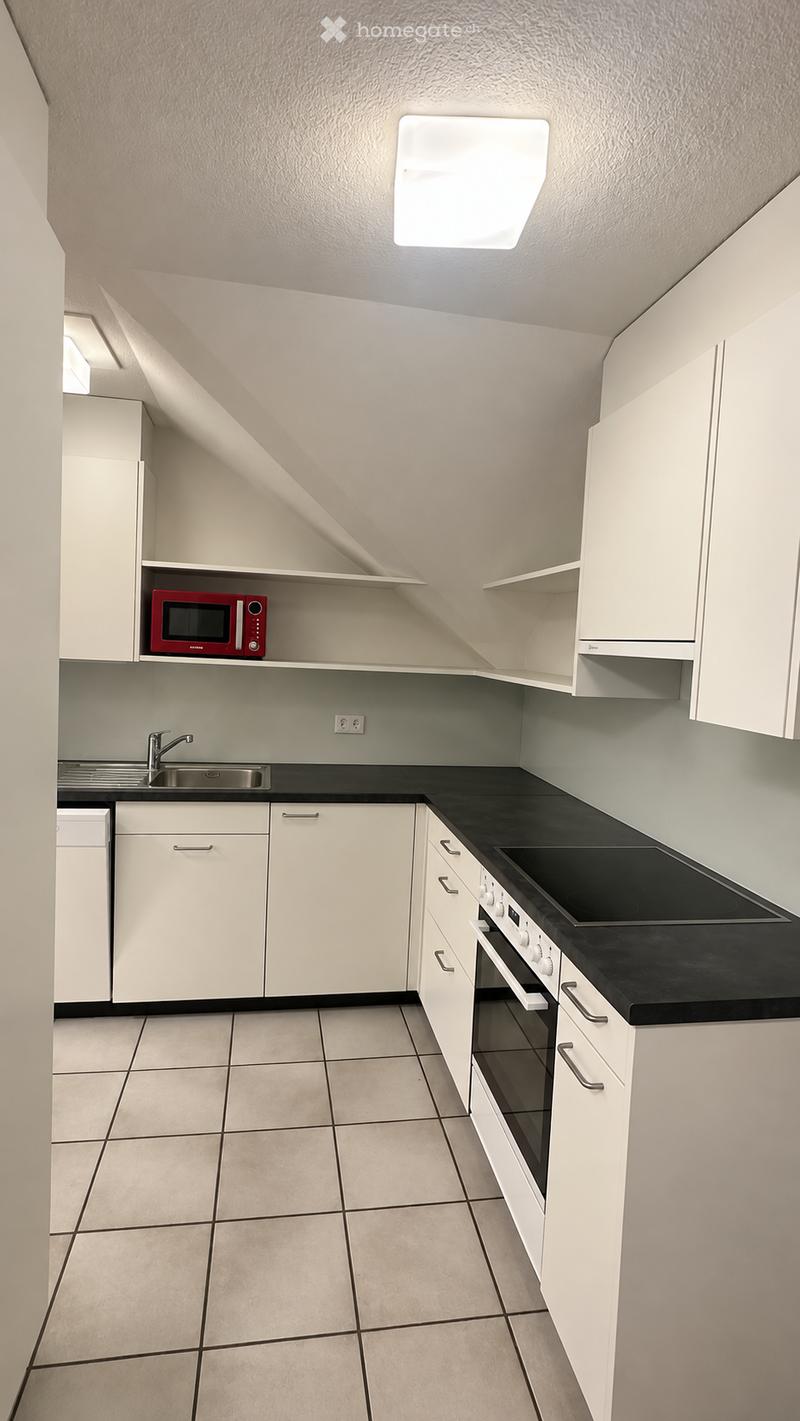 Modern kitchen with white cabinets, black countertops, and tiled flooring. Features a microwave, sink, stove, and oven.