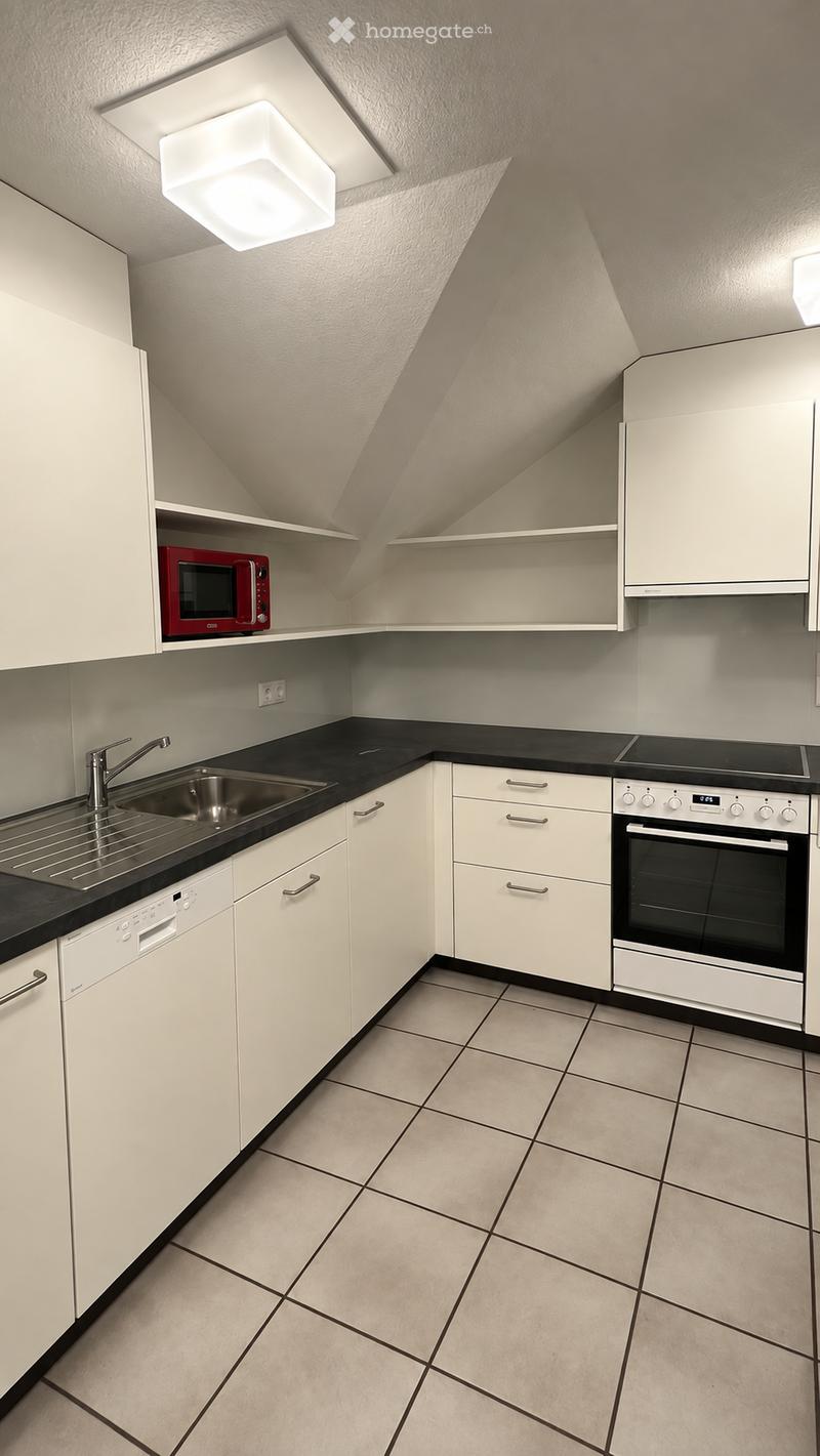 Modern kitchen with white cabinets, black countertops, stainless steel sink, and built-in appliances including an oven, microwave, and dishwasher.