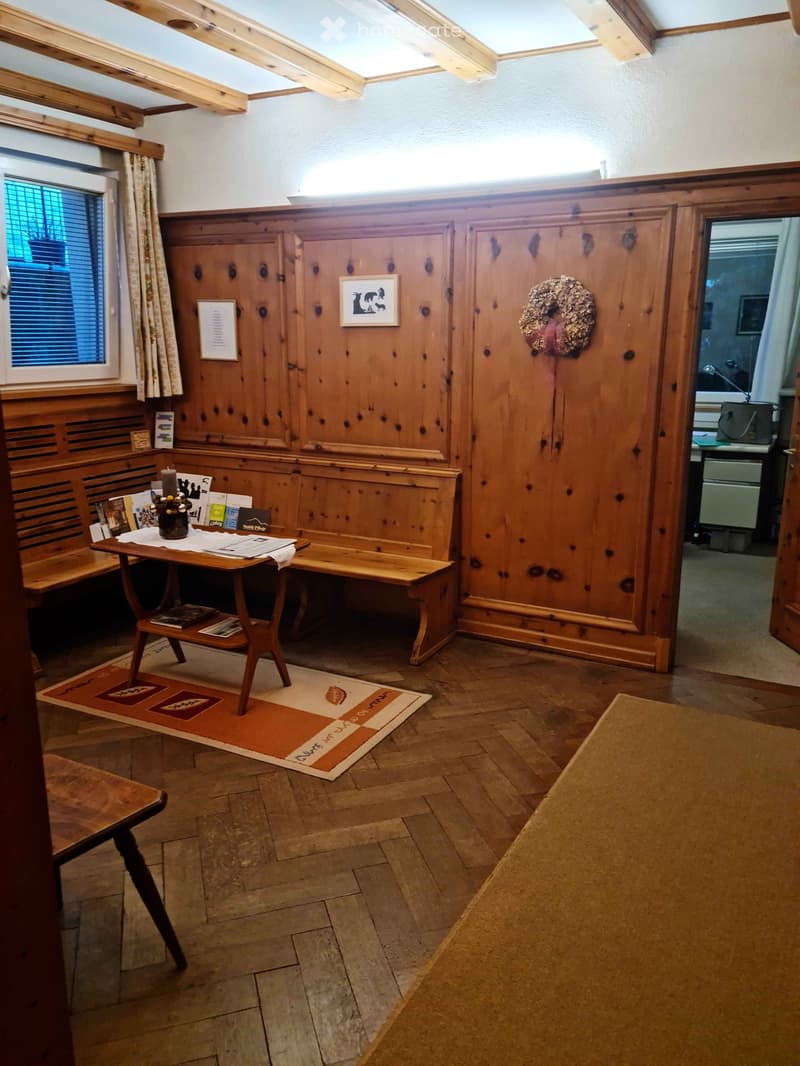 Wooden-paneled room with a small table, bench seating, picture frame, wreath, and candle on the table.