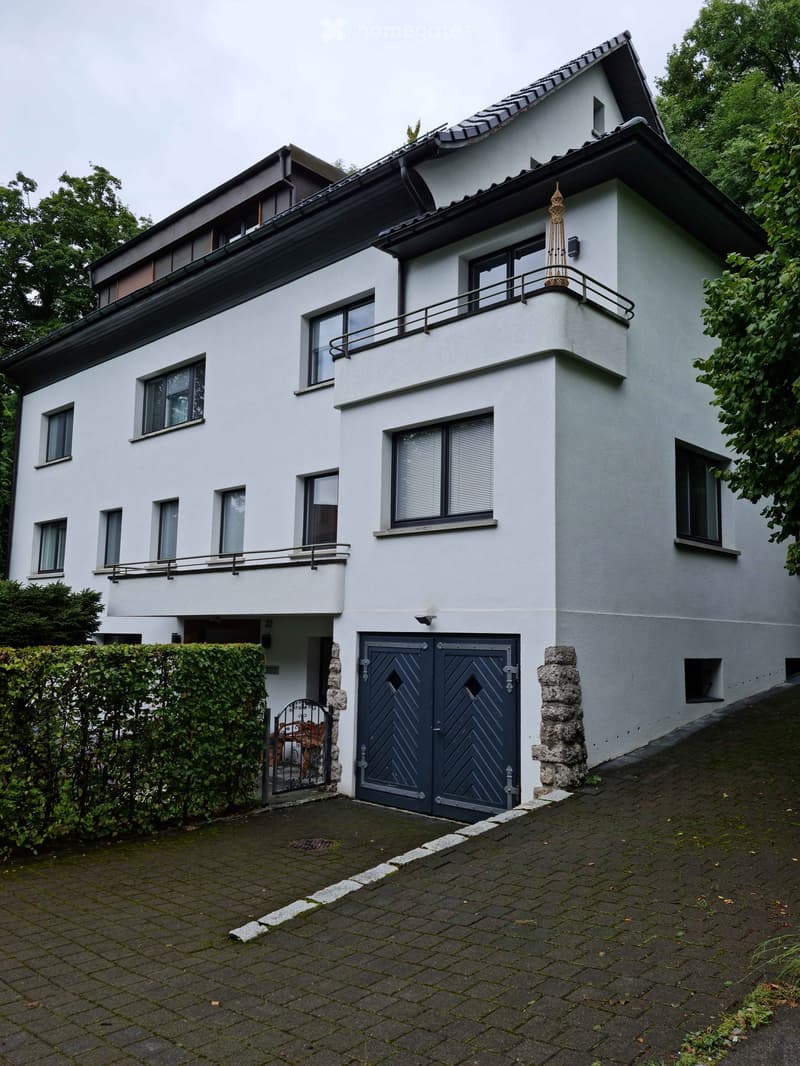 Two-story white house with multiple windows, a garage, and a small balcony on the upper level.