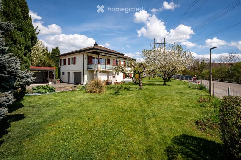 Two-story house with white exterior, red shutters, balcony, garage, and well-maintained lawn.