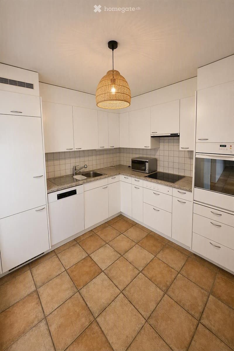 Modern kitchen with white cabinets, granite countertops, and tiled floor. Features a sink, microwave, oven, and dishwasher.