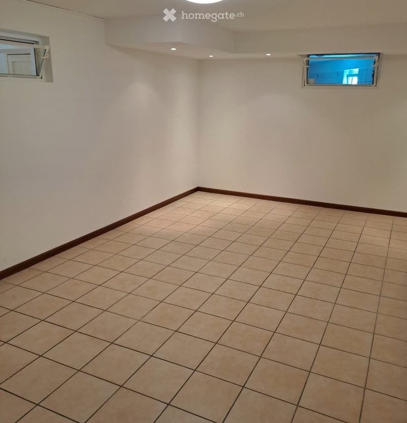 Empty room with tiled floor and white walls, featuring a small window and a ceiling light fixture.