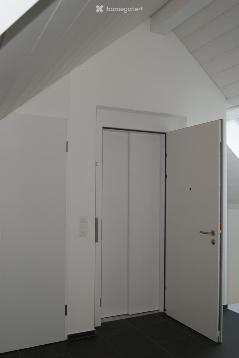 Empty hallway with white walls, black tiled floor, and a partially open sliding door leading to another room.