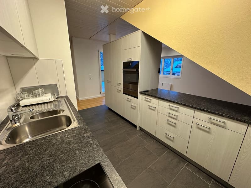 Modern kitchen with granite countertops, stainless steel sink, built-in oven, and white cabinets.
