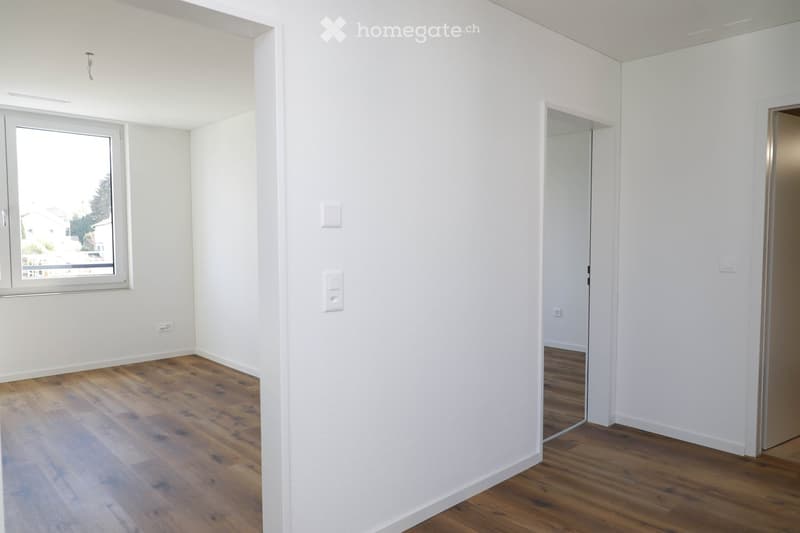 Empty room with white walls, wooden flooring, and a window with a view of the outside. No furniture or equipment is present.
