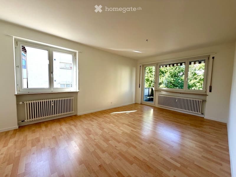 Empty room with wooden flooring, large windows, and radiators along the walls. No furniture or equipment present.