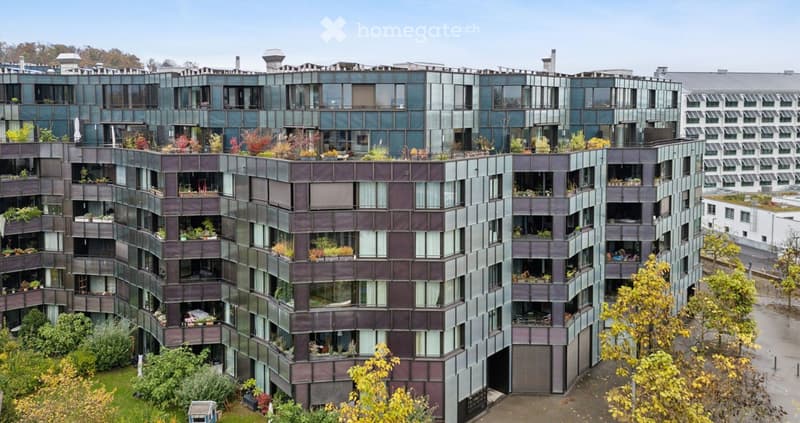 Modern multi-story residential building with a sleek, contemporary design, featuring numerous balconies and rooftop greenery.