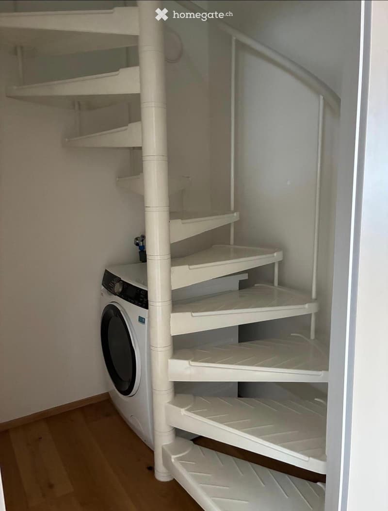 A compact bathroom with a washing machine and built-in white shelves for storage.
