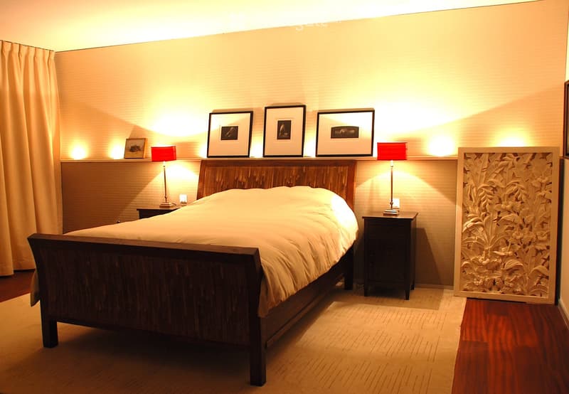 Cozy bedroom with a wooden bed, nightstands, lamps, and picture frames on the wall.