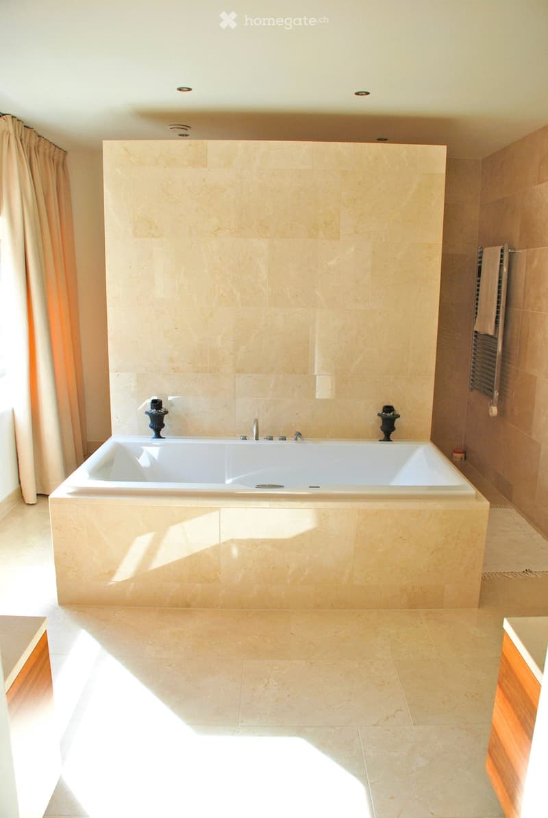 Luxurious bathroom with a large, freestanding bathtub, marble tiles, and a towel rack with a towel.