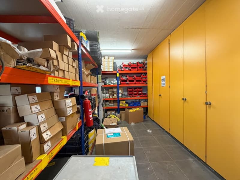 Storage room with metal shelving units, cardboard boxes, and various storage containers. Yellow cabinets line one wall.