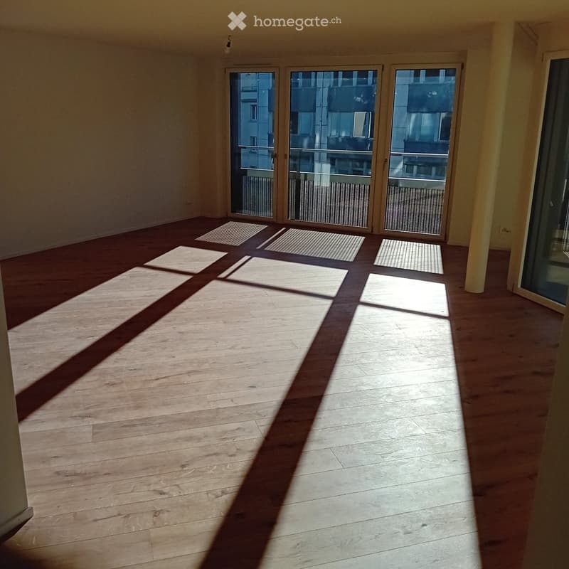 Empty room with wooden flooring and large glass sliding doors leading to a balcony area.