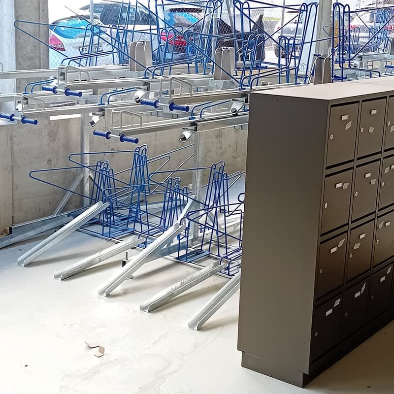 An empty room with a concrete floor, a metal filing cabinet, and a large metal structure with blue handles and silver bars, likely part of a workshop or storage area.