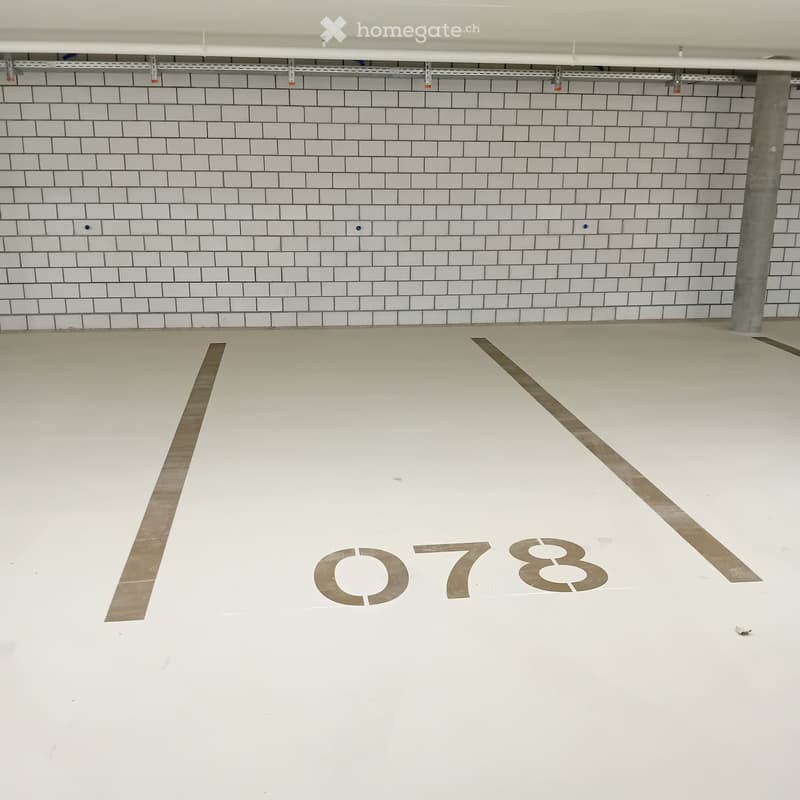 Empty room with white tiled walls and a white floor, marked with the number "078" in the center.