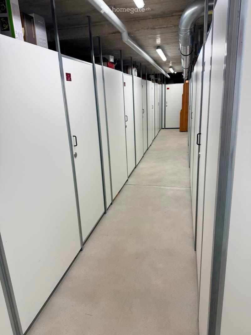 Clean, modern hallway with white lockers on both sides, concrete floor, and exposed ceiling beams.