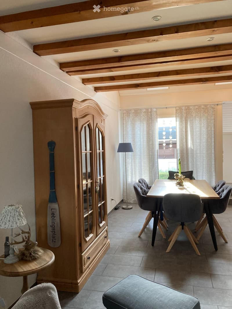 Dining room with wooden cabinet, dining table, chairs, lamps, and decorative items.