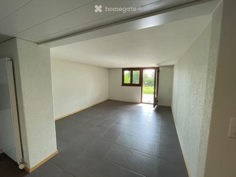 Empty room with grey tiled floor, white walls, and a window with a door leading outside.