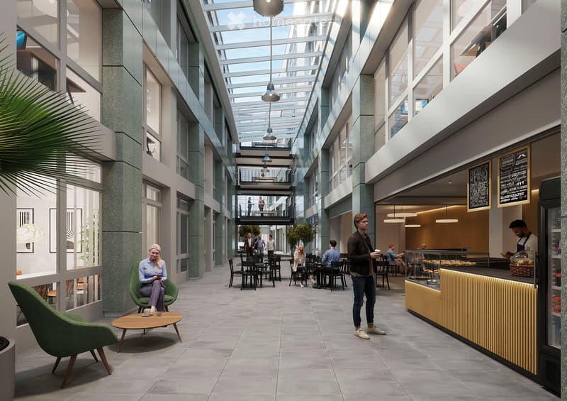 Modern, open-plan lounge area with a mix of seating, tables, and a coffee bar. The space features contemporary furniture, large windows, and a high ceiling with exposed lighting fixtures.