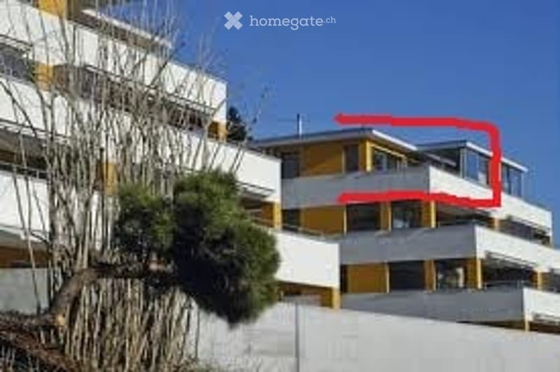Multi-story residential building with yellow and white facade, balconies, and trees in the foreground.