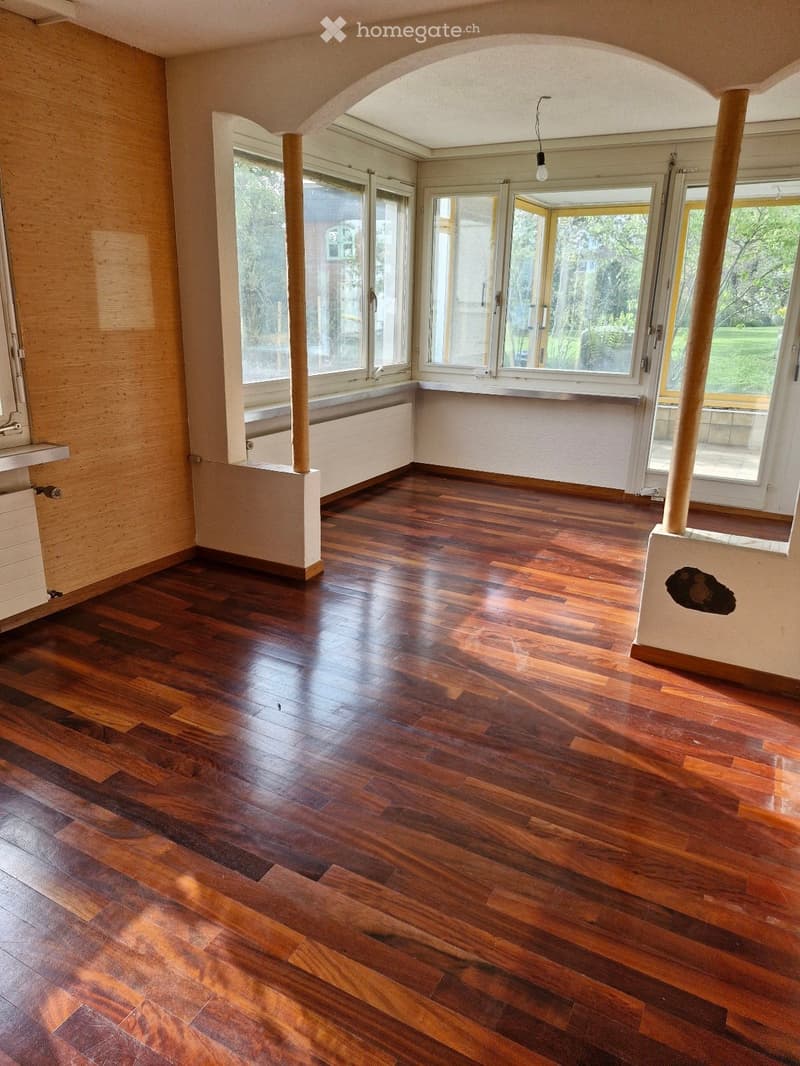 Empty room with wooden flooring, large windows, and white walls. No furniture or equipment present.