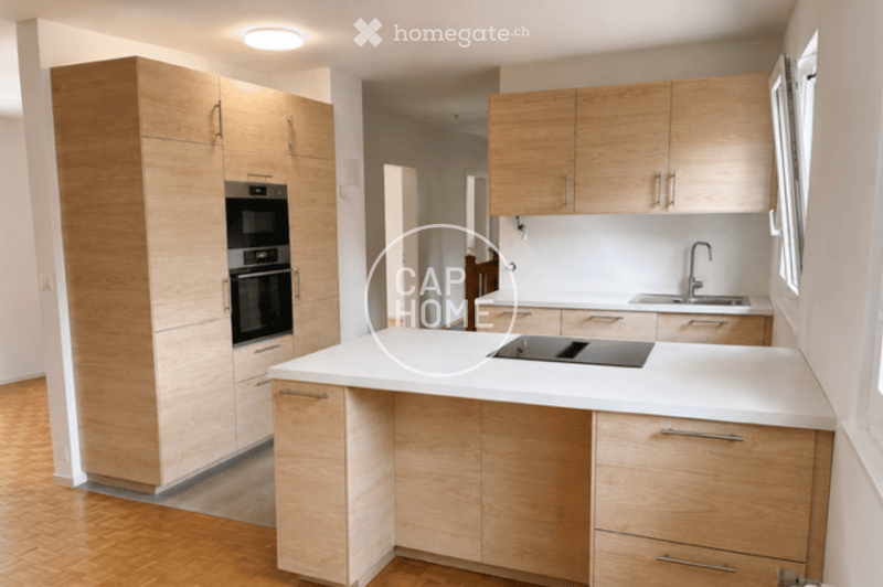 Modern kitchen with light wooden cabinets, white countertop, built-in oven, sink, and induction cooktop.