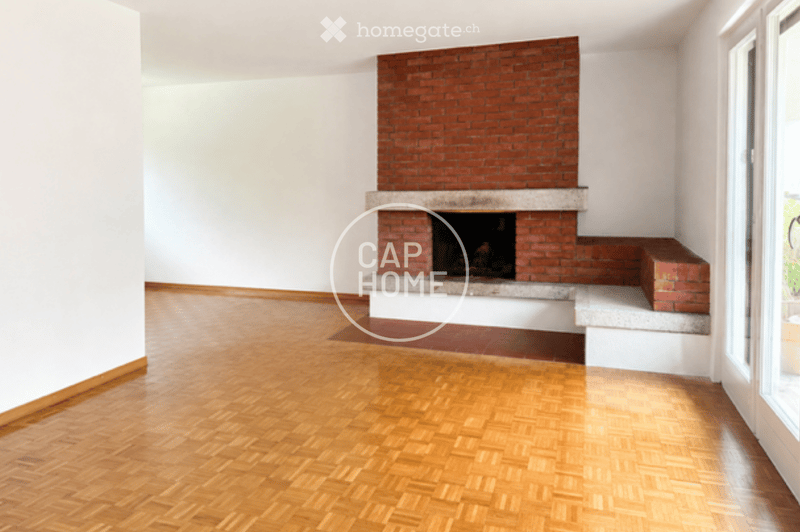 Empty room with wooden flooring and a brick fireplace against one wall.