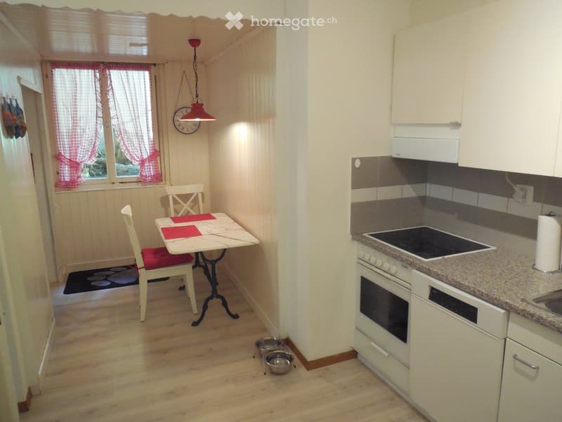 Cozy kitchen and dining area with white cabinets, granite countertop, electric stove, and a small dining table with chairs.