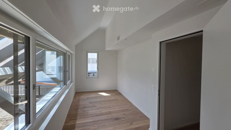Empty room with wooden flooring, white walls, large windows, and a closed door.