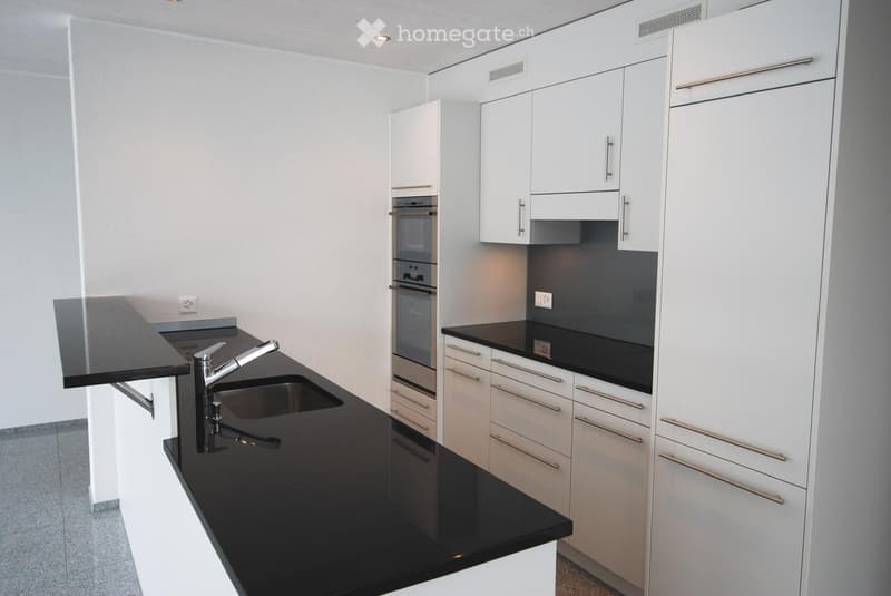 Modern kitchen with white cabinets, black countertops, and stainless steel fixtures.