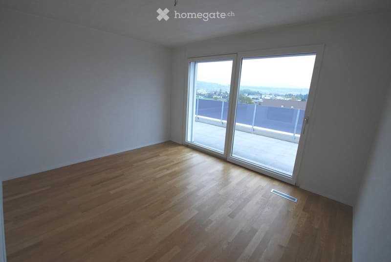 Empty room with wooden flooring and large sliding glass doors leading to a balcony or terrace.