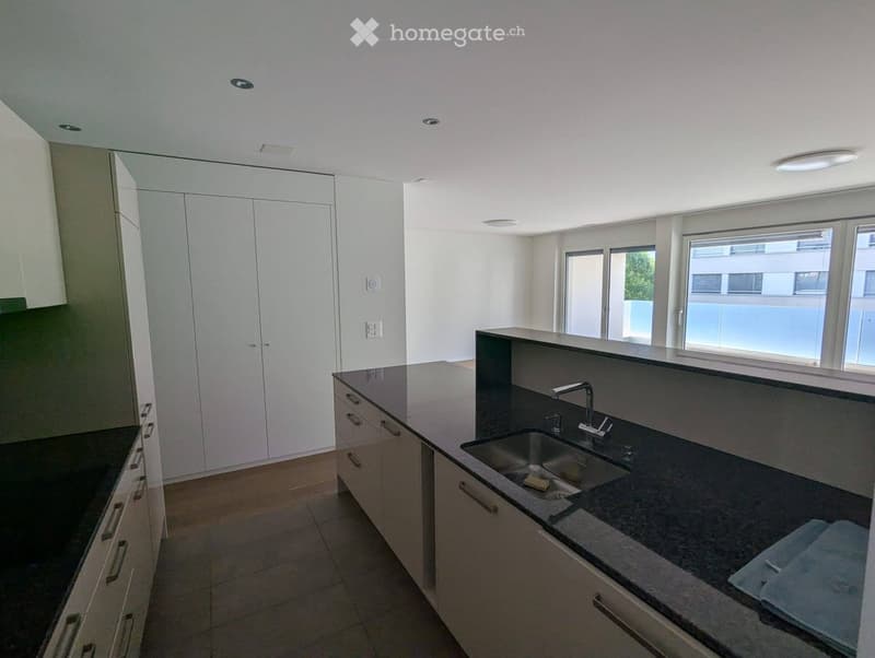 Modern kitchen with white cabinets, dark countertops, and a stainless steel sink.