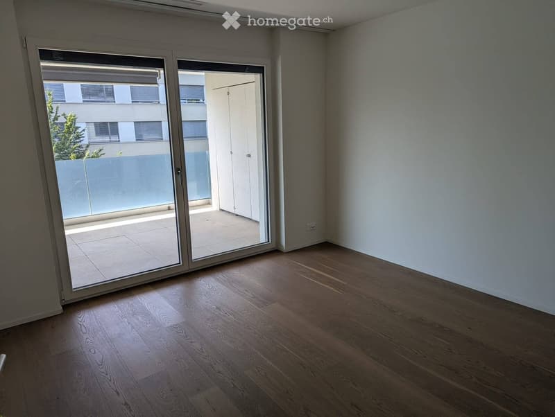 Empty room with wooden flooring and large sliding glass doors leading to a balcony area.