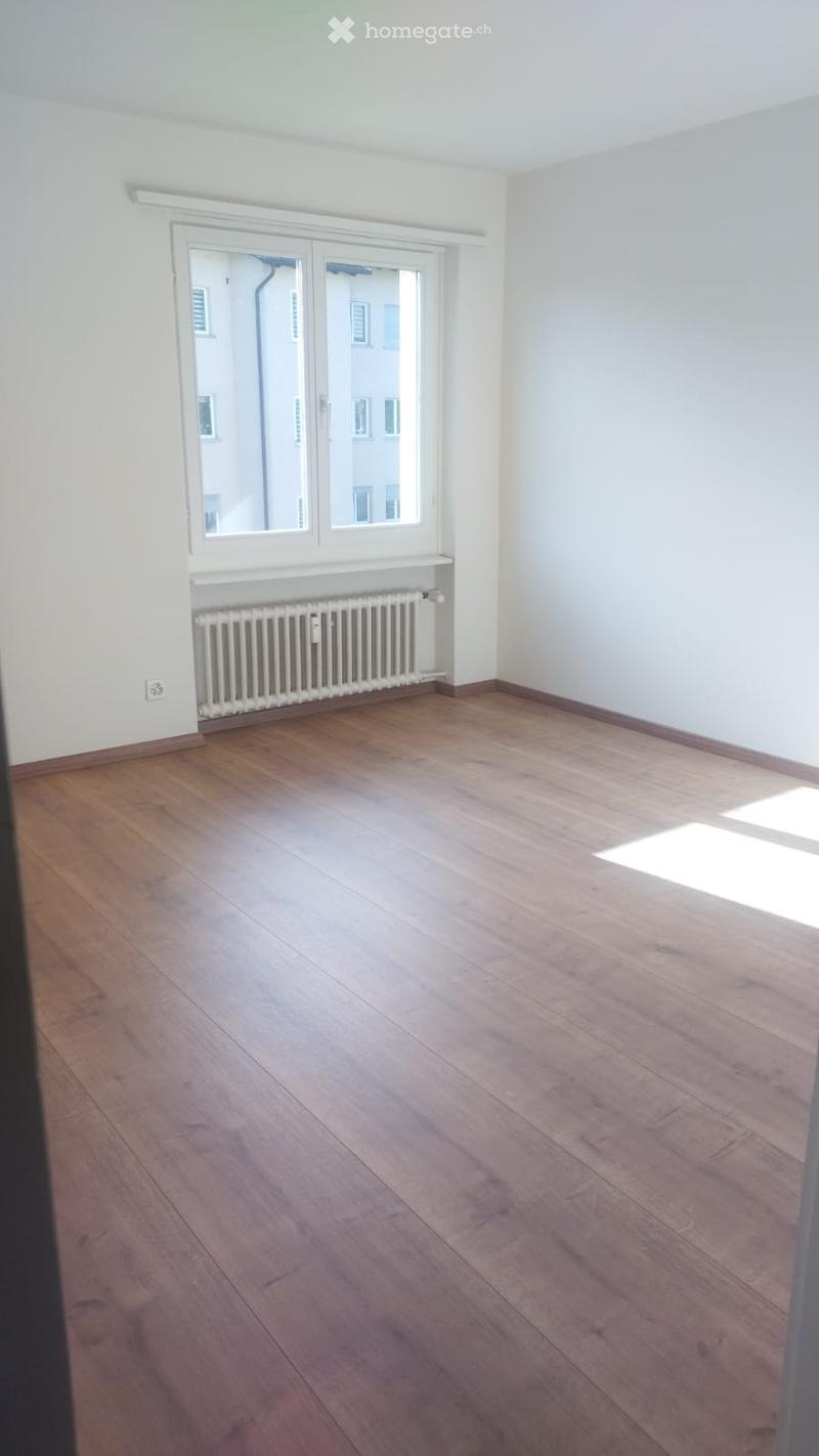 empty room, hardwood floors, white walls, large window, radiator, power outlet
