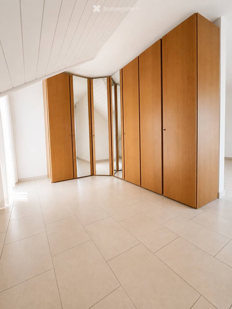 Empty hallway with light-colored tiled flooring, white walls, and large wooden sliding doors with mirrored panels.
