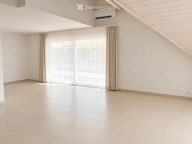 Empty room with light-colored tiled flooring, white walls, large window with beige curtains, and an air conditioning unit mounted on the wall.