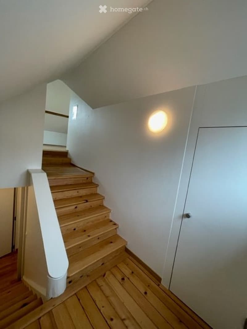 Wooden staircase with white walls and a built-in light fixture, leading to an upper level.