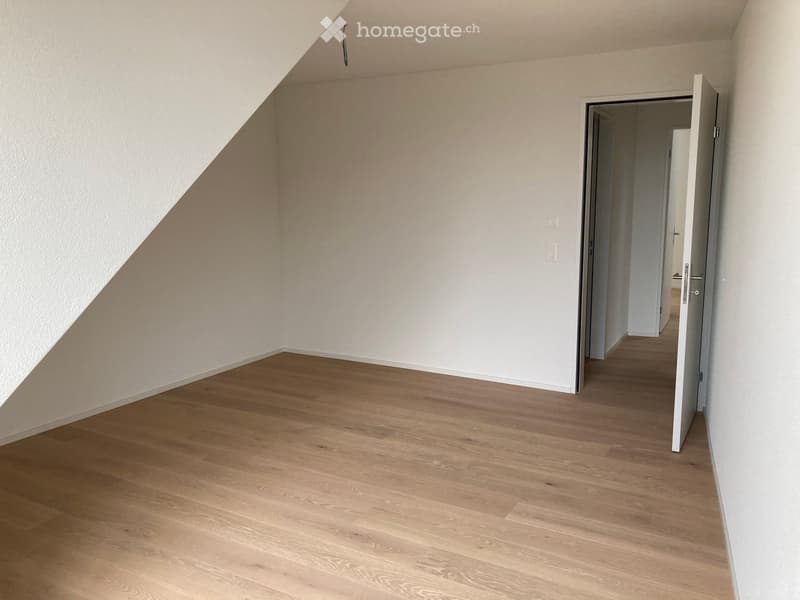 Empty room with wooden flooring and white walls, featuring an open doorway leading to another space.