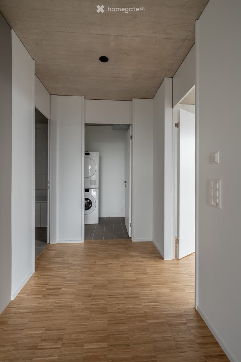 wooden floor, white walls, washer and dryer, tile flooring in the middle