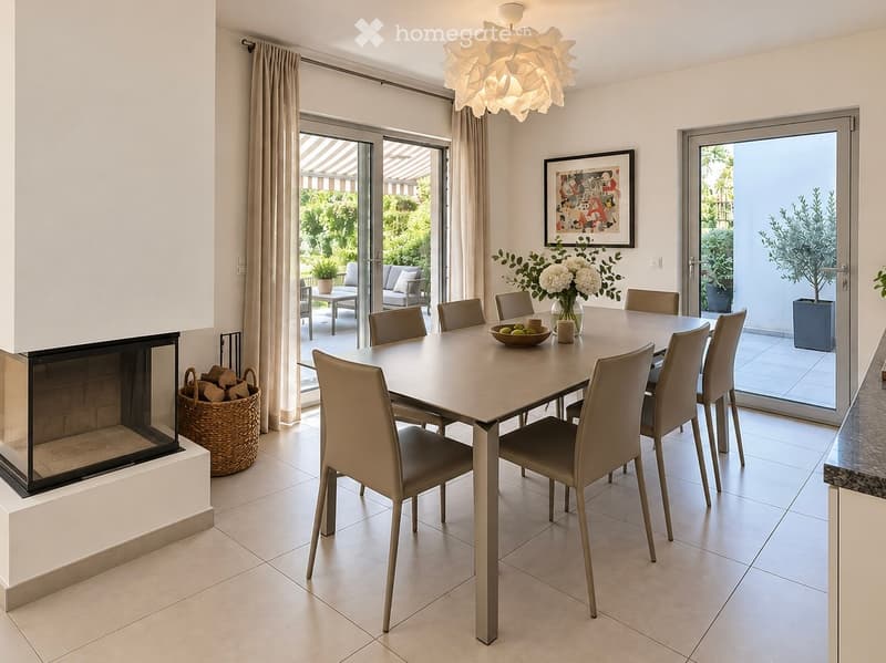 Modern dining room with a large dining table, chairs, fireplace, and large windows offering a view of the garden.