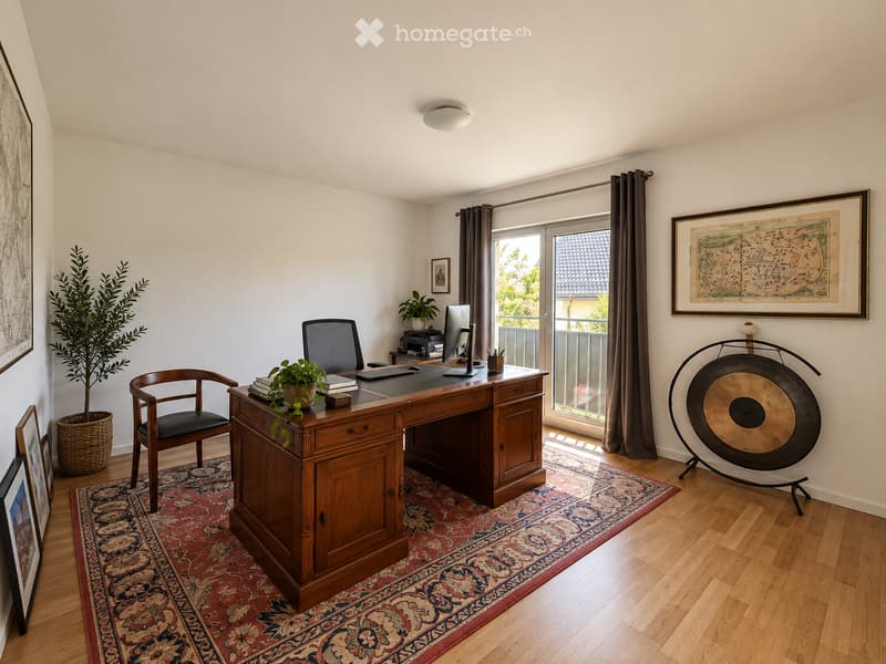 A well-lit, modern office space with a wooden desk, ergonomic chair, computer monitor, and decorative items including a large gong, potted plants, and framed artwork.