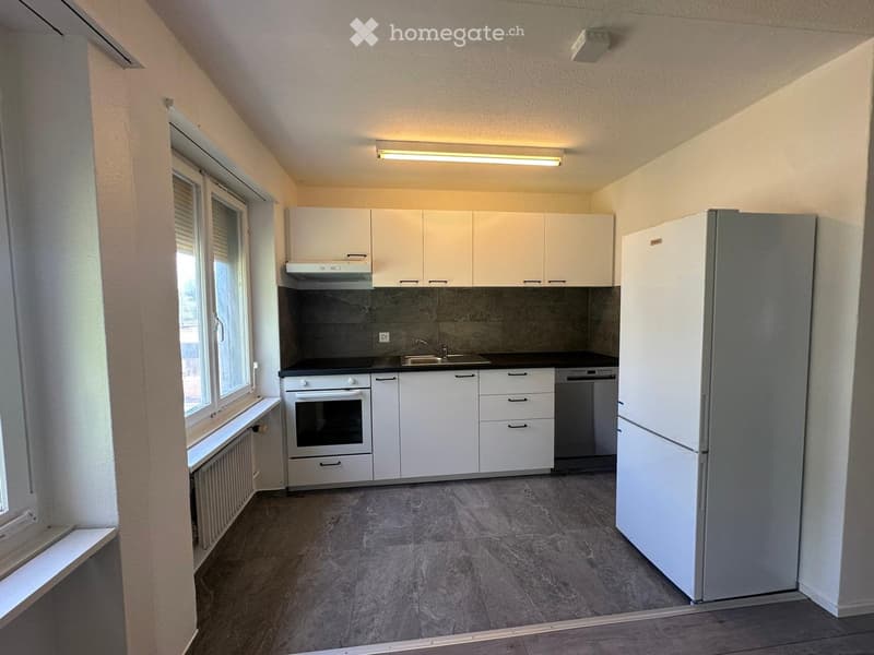 Modern kitchen with white cabinets, stainless steel appliances, and grey tiled flooring.