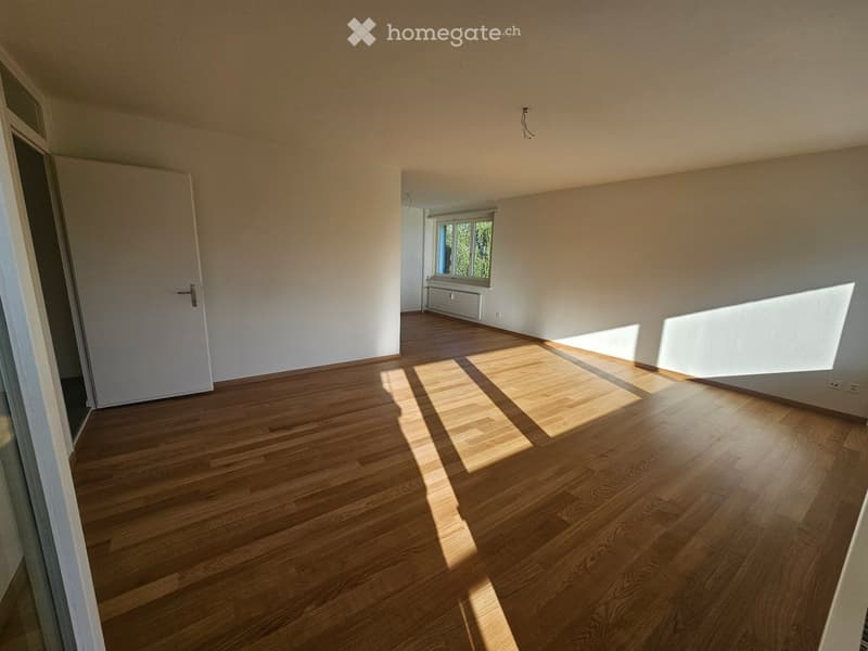 Empty room with wooden flooring, white walls, and a window letting in natural light. No furniture or equipment is present.