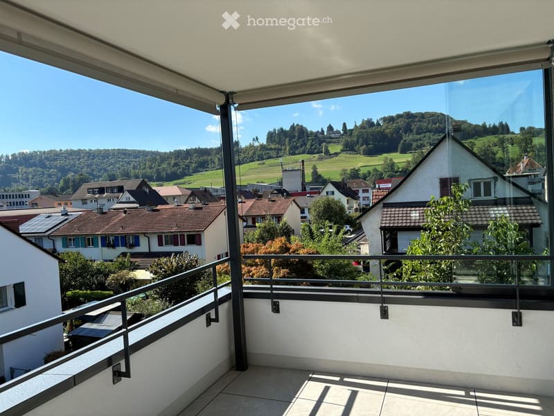 Balcony with glass railings, tiled floor, view of the town and mountains