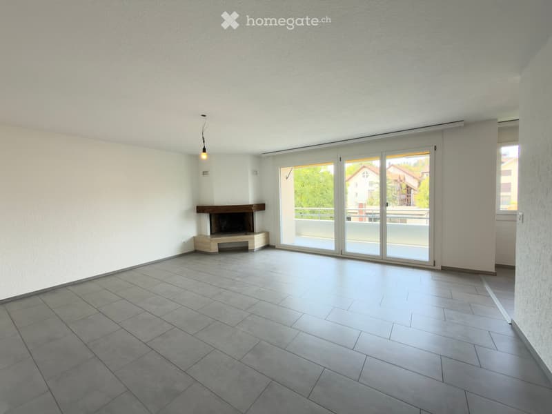 Empty room with white walls, tiled floor, fireplace, and large sliding glass doors leading to a balcony.