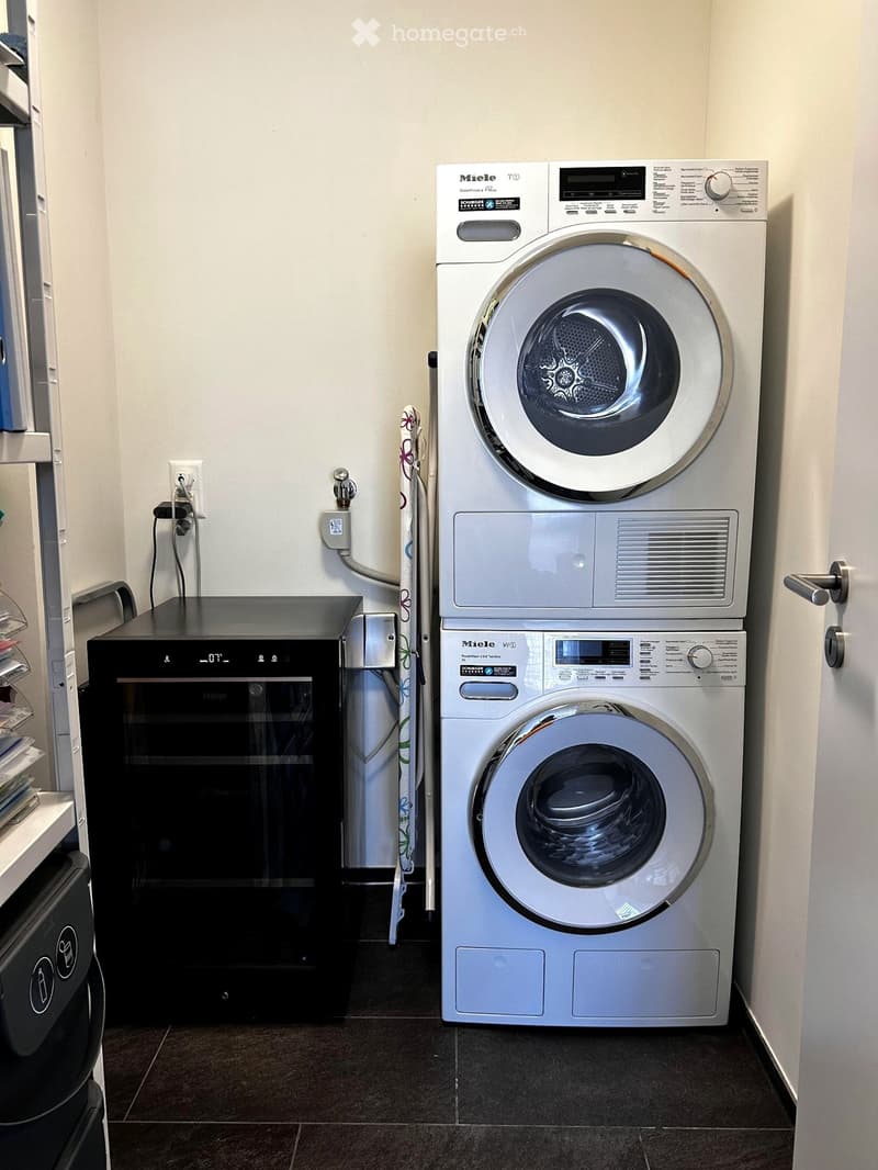 Modern bathroom with a white Miele washing machine and a black Haier dishwasher, both stacked vertically.