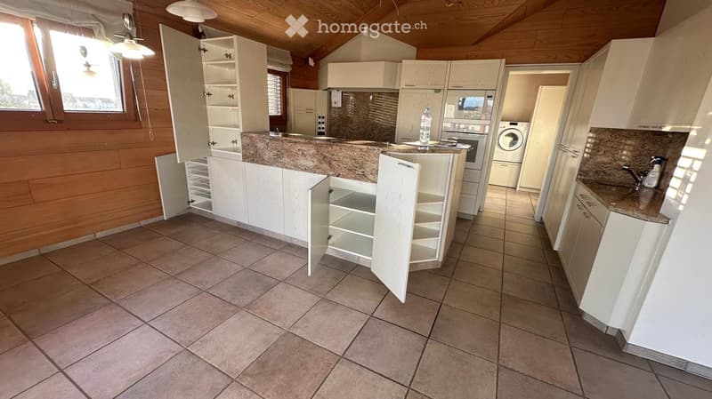 Modern kitchen with white cabinets, granite countertops, and tiled flooring. Features an open shelving unit, sink, oven, and washing machine.