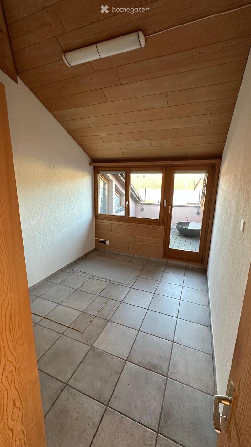 Empty hallway with wooden ceiling, tiled floor, and sliding glass doors leading to an outdoor area with a bowl-shaped planter.